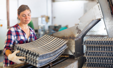 Woman carrying cell seed trays in agricultural facility