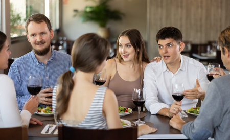 Group of friends talking and eating in restaurantの写真素材
