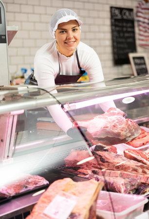 Young woman puts piece of beef in showcaseの写真素材