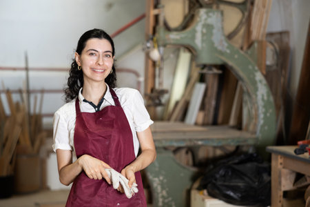 Employee of workshop cuts wooden board into parts using sawの写真素材