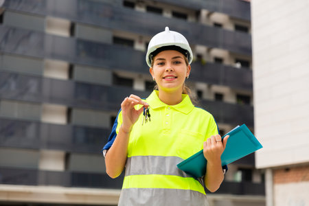 Young woman on building site showing keyの写真素材