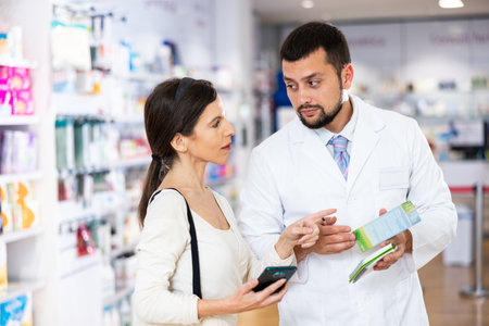 Male pharmacist consulting woman customer in drugstoreの写真素材