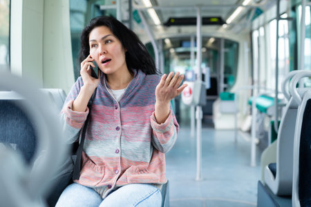 Oriental woman talking on mobile phone while riding a tramの写真素材