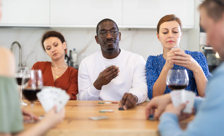 African American man playing poker with friends at kitchen table