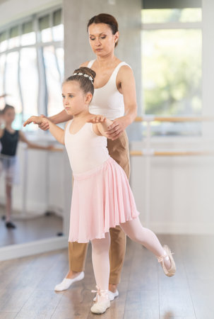 In studio, mentor corrects girls arm and leg, teaches correct dynamics and execution of movements