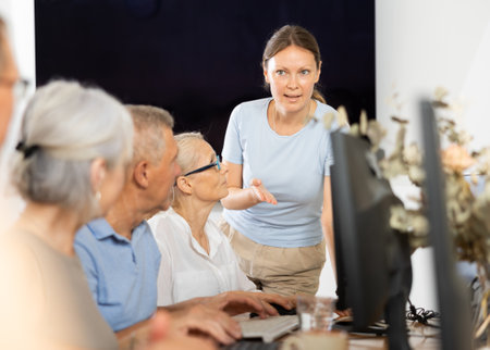 Female teacher conducting group lesson of computer skills to older peopleの写真素材
