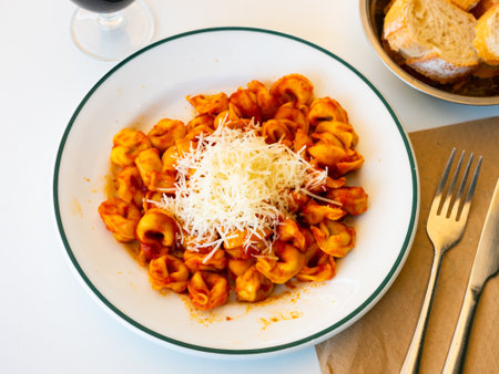 Tortellini with tomatoes, tomato gravy, and grated parmesan cheese is placed in the center of the dishの写真素材