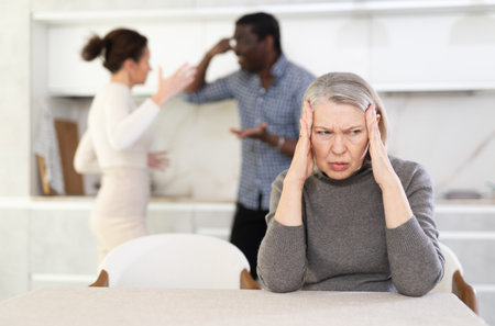 Elderly sad woman sits at table during family quarrelの写真素材