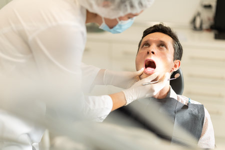 Young female dentist examining male patientの写真素材