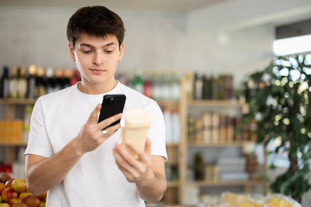 Male buyer checks suitability - scans QR code on jar of mayonnaise label in grocery storeの写真素材