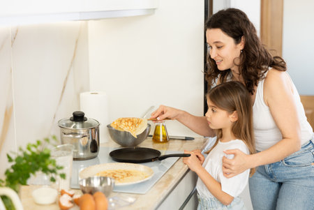 Mom and her daughter fry pancakesの写真素材