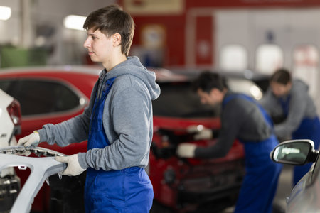 Service station young man employee works in repair box, department
