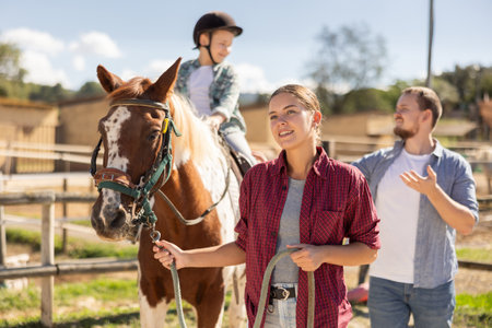 Young woman leading horse with boy on horsebackの写真素材