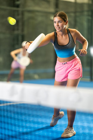 Portrait of girl paddle tennis player during friendly doubles couple match at courtの写真素材