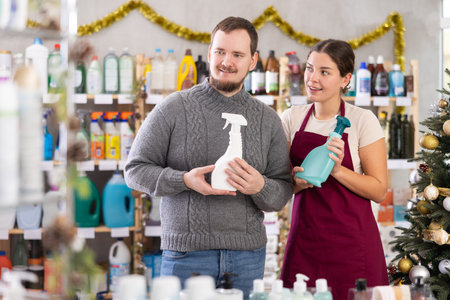 Professional young woman seller offers spray to male client in store. Christmas shoppingの写真素材