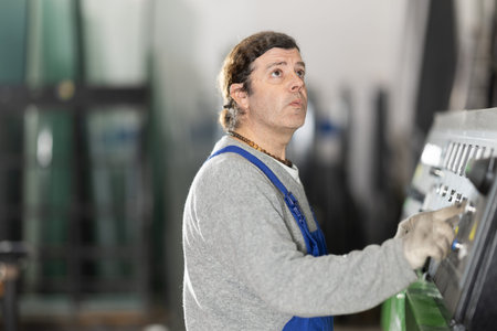 Man workshop employee switches toggle switch on control panel