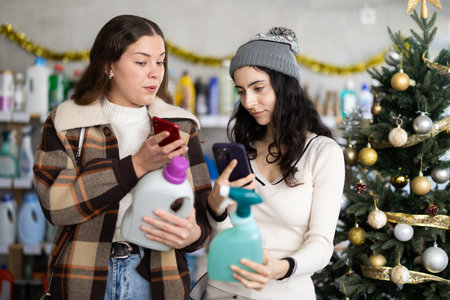 Young girls scanning QR-code on cleaning spray in store during Christmasの写真素材