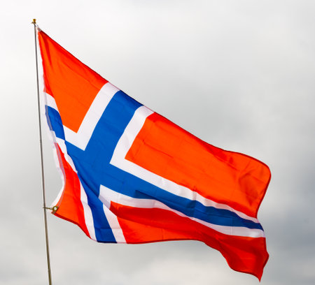 Flag of norway flying with pride with blue sky as backgroundの写真素材