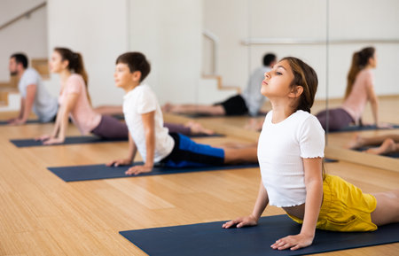 Girl doing stretching asana Upward Facing Dog during family yoga workoutの写真素材