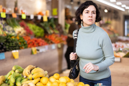Adult woman choosing fruits and vegetables in vegetable shopの写真素材