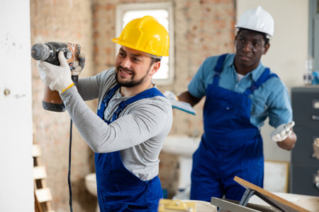 Professional builder drills a wall with a hammer drillの写真素材