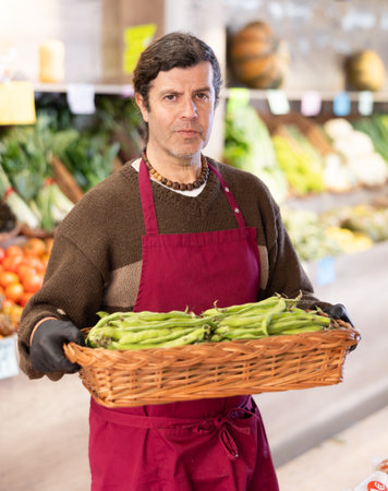 Adult man seller with basket of green peasの写真素材