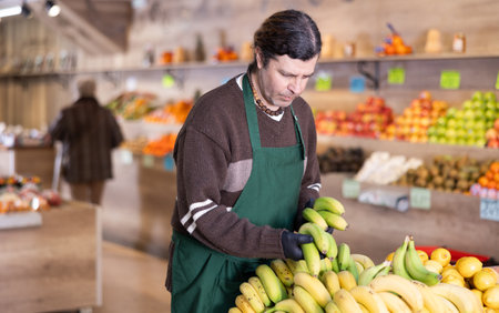 Man shop seller puts banana goods on display caseの写真素材