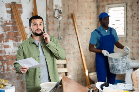 Man designer talking on phone about documents in construction siteの写真素材