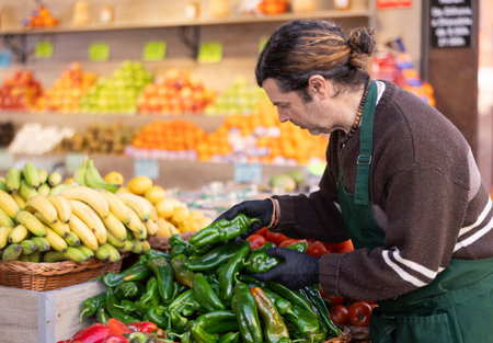 Man shop seller puts pepper goods on display caseの写真素材