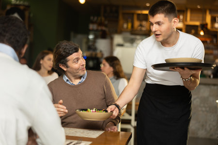 Waiter guy brings an order for menの写真素材