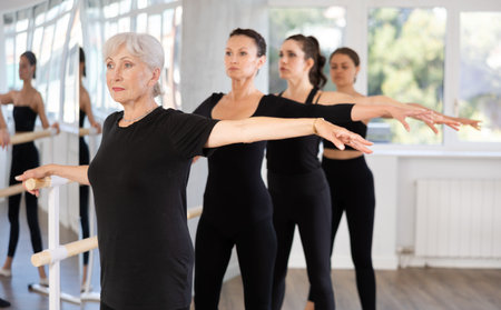 Senior woman maintaining second position at ballet barreの写真素材
