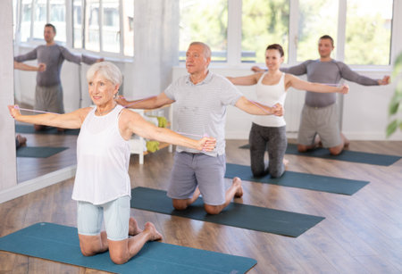 Mature woman bring together and spread your straightened arms at chest level with resistance bandの写真素材