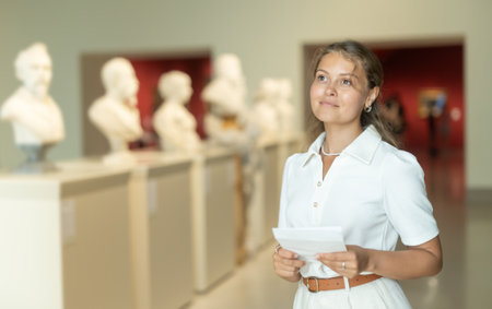 Woman with sheet piece of paper in hands view sculpture in museum hallの写真素材