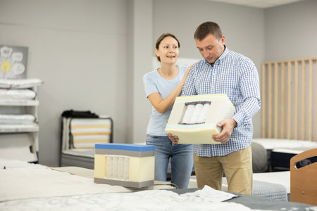 Couple inspecting samples of mattress constructions in furniture shopの写真素材