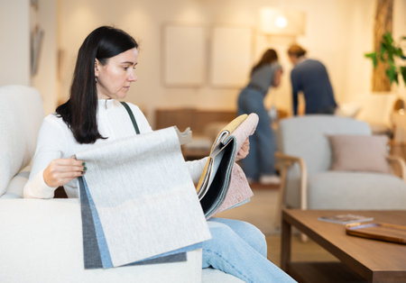 Woman deciding on material for couch in furniture shopの写真素材