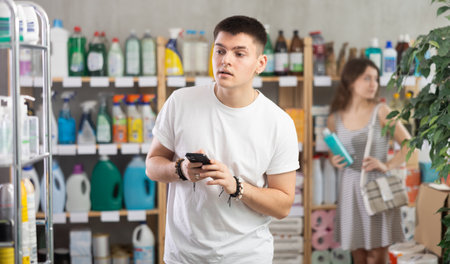 Man holding mobile in his hands while standing in supermarketのeditorial素材