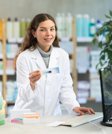 Woman pharmacist offering ointment in pharmacyの写真素材