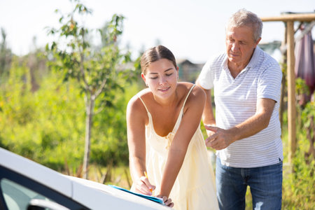Elderly man and young woman sign document on carの写真素材
