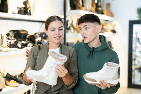 Couple man and woman choosing winter boots in storeの写真素材
