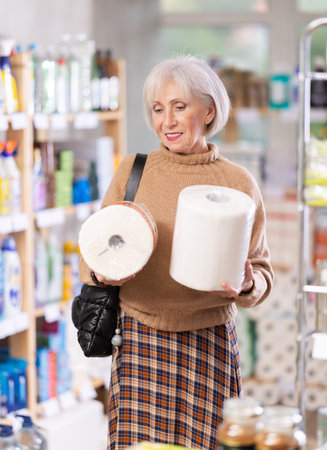 Positive mature woman choosing paper roll tissue in department storeの写真素材
