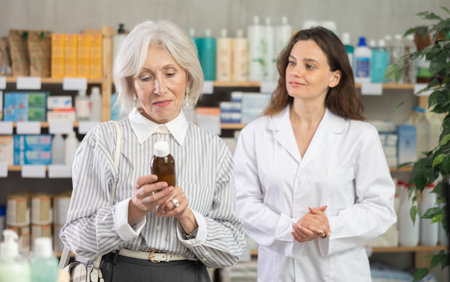 Mature woman choose antitussive syrup, woman pharmacist offers similar itemの写真素材