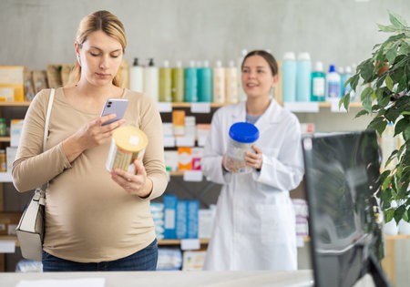 Pregnant woman buyer scans baby formula qr code with woman pharmacistの写真素材