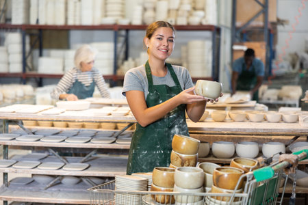 Cheerful young woman ceramist in workshopの写真素材