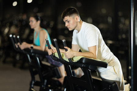 In gym, guy uses gym apparatus to strengthen leg muscles