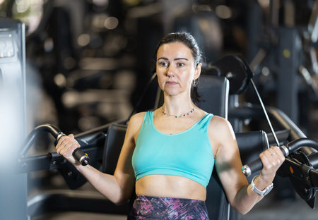 Sporty woman doing triceps curls on gym machine