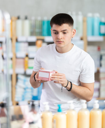 young guy chooses packages of pills in a pharmacyの写真素材