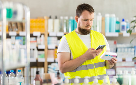 Male builder scans code on package to check expiration dateの写真素材