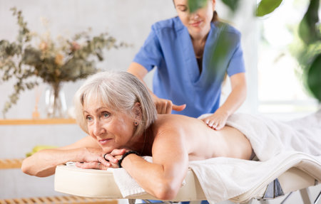 Young woman doing back massage to elderly womanの写真素材