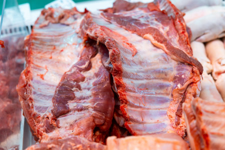 Raw pork rib tips in packing tray on glass window refrigerator of meat shop
