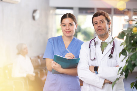 Experienced doctor standing with young female assistantの写真素材